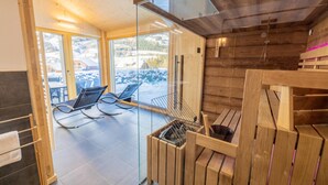 A modern bathroom with a glass shower enclosure, wooden flooring, and a view of a snowy landscape.