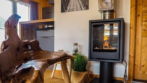 Ein gemütliches Zimmer mit Holztisch, Fernseher zeigt Kaminfeuer und rustikaler Einrichtung.