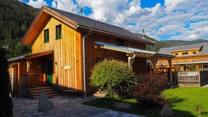 Eine Holzhütte mit einer Veranda, einer Steintreppe und einem gepflegten Garten.