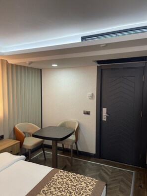 A hotel room with a bed, a table, two chairs, a door, and a wall-mounted air conditioning unit. - Hotel Eronur (Bilecik)