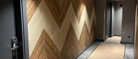 A hallway with a chevron-patterned wall, a number sign indicating room 305, and a patterned carpet.