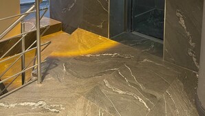 A modern elevator with a digital display, a marble wall with a light fixture, and a metal staircase. - Hotel Eronur (Bilecik)