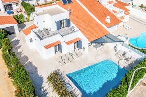 Uma área de piscina no terraço com piscina retangular, espreguiçadeiras e um espaço de estar coberto.