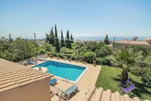 A swimming pool with lounge chairs and a view of the sea.