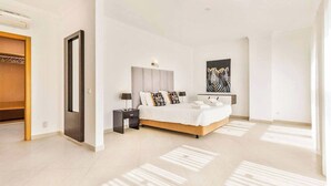 A modern bedroom with a large bed, bedside tables, a wardrobe, and a zebra artwork on the wall. - Villa Cabrita de Parra (Albufeira)