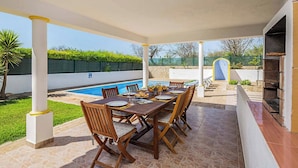 An outdoor patio with a pool, a dining table set for six, and a barbecue grill. - Villa Cordyline (Albufeira)