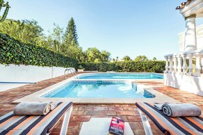 Ett poolområde med två bubbelpooler, solstolar och en bok som ligger på en handduk.