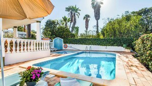 A swimming pool with a sunshade, a lifeguard stand, and a decorative fence. - Villa Cardona (Albufeira)