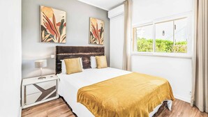 A modern hotel room with a large bed, a nightstand, and two wall-mounted paintings. - Villa Corcovada (Albufeira)