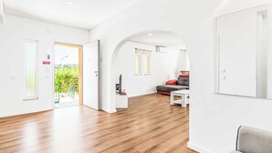 A spacious living area with a wooden floor, a sofa, a coffee table, and a TV. - Villa Corcovada (Albufeira)