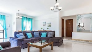 A modern living room with a sectional sofa, a glass coffee table, and a staircase leading to an upper floor. - Villa Bonita Gale (Albufeira)