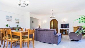 A modern living room with a dining area, a sofa, and a television. - Villa Bonita Gale (Albufeira)