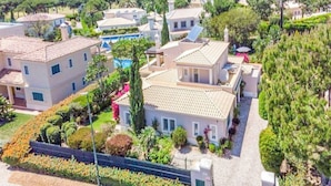 Un quartier résidentiel comprenant plusieurs maisons, une piscine et des jardins bien entretenus.