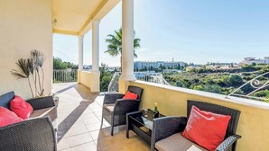 Ein Balkon mit Korbmöbeln, einem Tisch und einer Champagnerflasche.