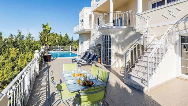 Eine Dachterrasse mit Pool, Liegestühlen und einem für das Frühstück gedeckten Esstisch.