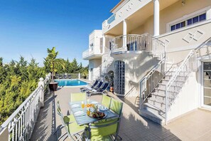 Une terrasse sur le toit avec une piscine, des chaises longues et une table à manger préparée pour le petit-déjeuner.