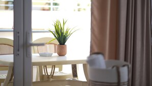 A dining area with a table, chairs, a potted plant, and a white bowl. - Saranda Waterside Apartments (Sarandë)
