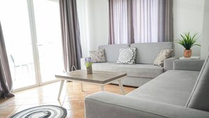 A modern living room with a grey sofa, a wooden coffee table, and a potted plant. - Saranda Waterside Apartments (Sarandë)