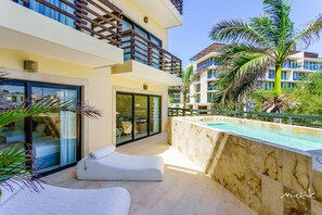 A modern hotel with a pool, outdoor seating, and a view of neighboring buildings.