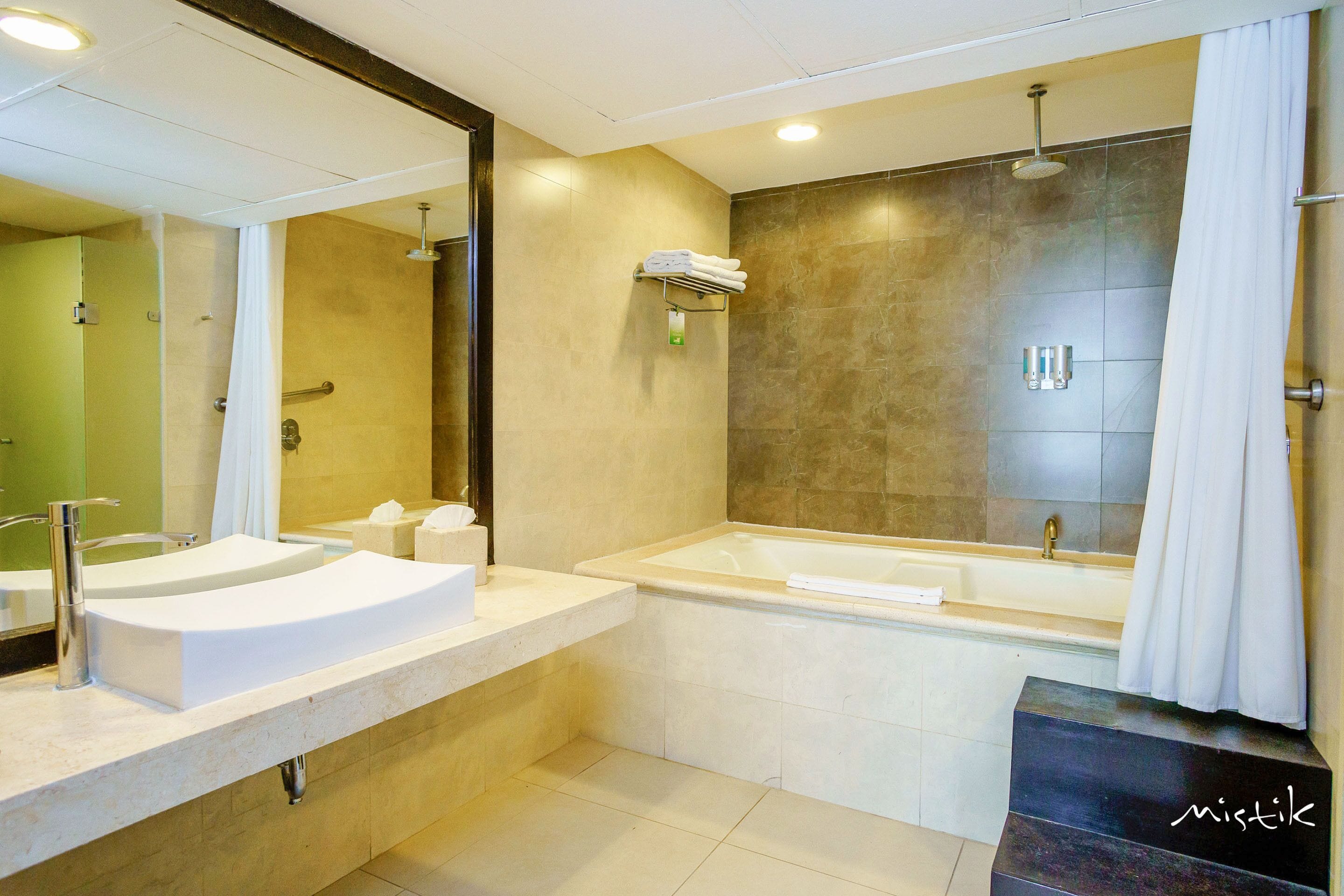 A modern bathroom with a double sink vanity, a bathtub, and a shower area.