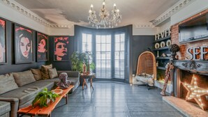 A spacious living room with a large window, a chandelier, a fireplace, and a sofa. - Eclectic modern victorian large city central flat  (Brighton and Hove)