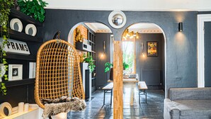 A modern interior with a wicker chair, a sofa, and a dining area with a wooden table and benches. - Eclectic modern victorian large city central flat  (Brighton and Hove)