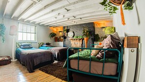 A cozy bedroom with two bunk beds, a brick fireplace, and various plants. - Eclectic modern victorian large city central flat  (Brighton and Hove)