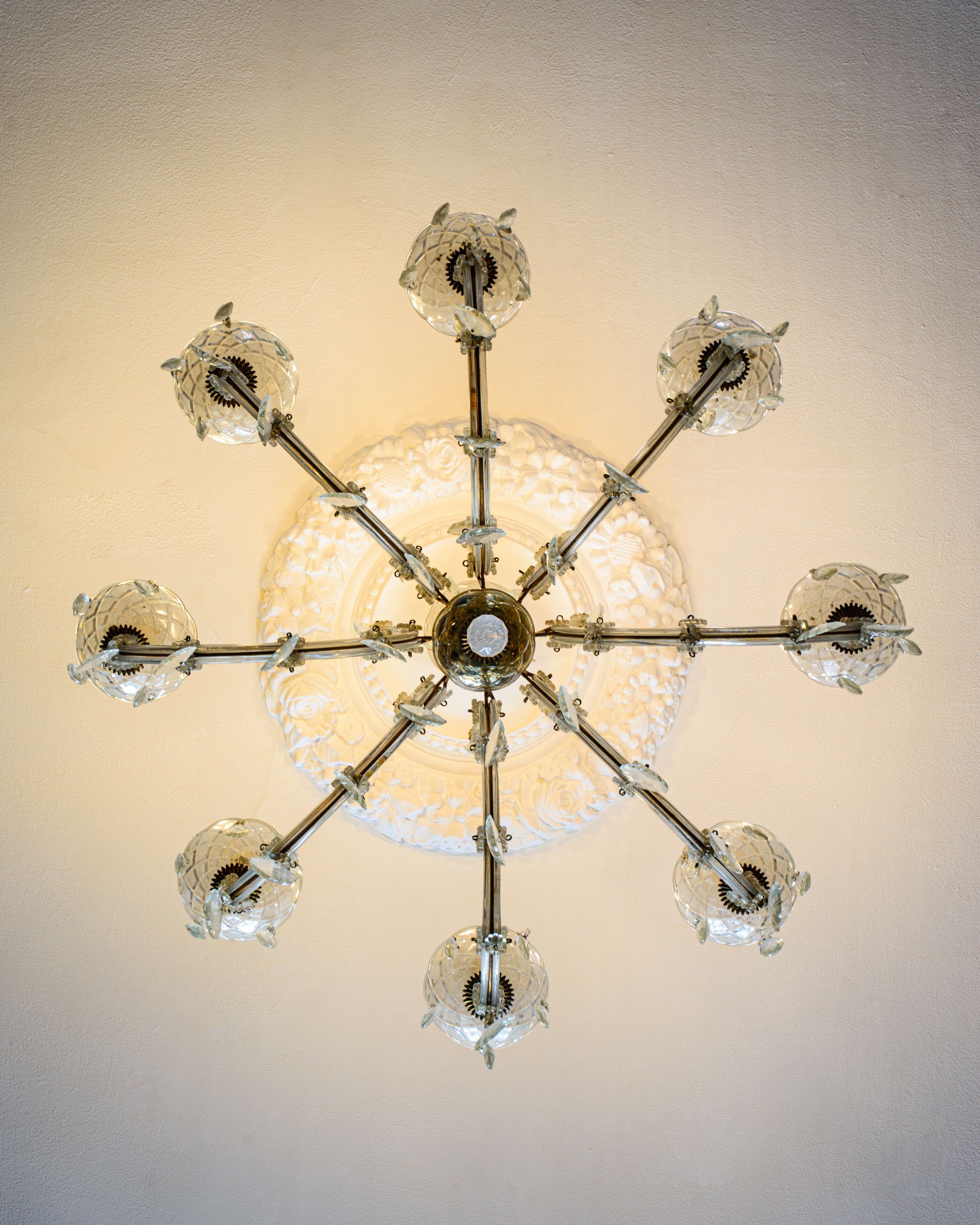 Um candelabro com uma esfera central e vários braços, cada um terminando em uma estrutura semelhante a cristal.
