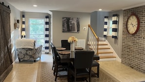 A dining area with a table set for four, a staircase, and a clock on the wall. - NEW! On a WATERFALL! Fiery Gizzard Lodge at Sycamore Falls! 13 bluff acres!  (Tracy City)