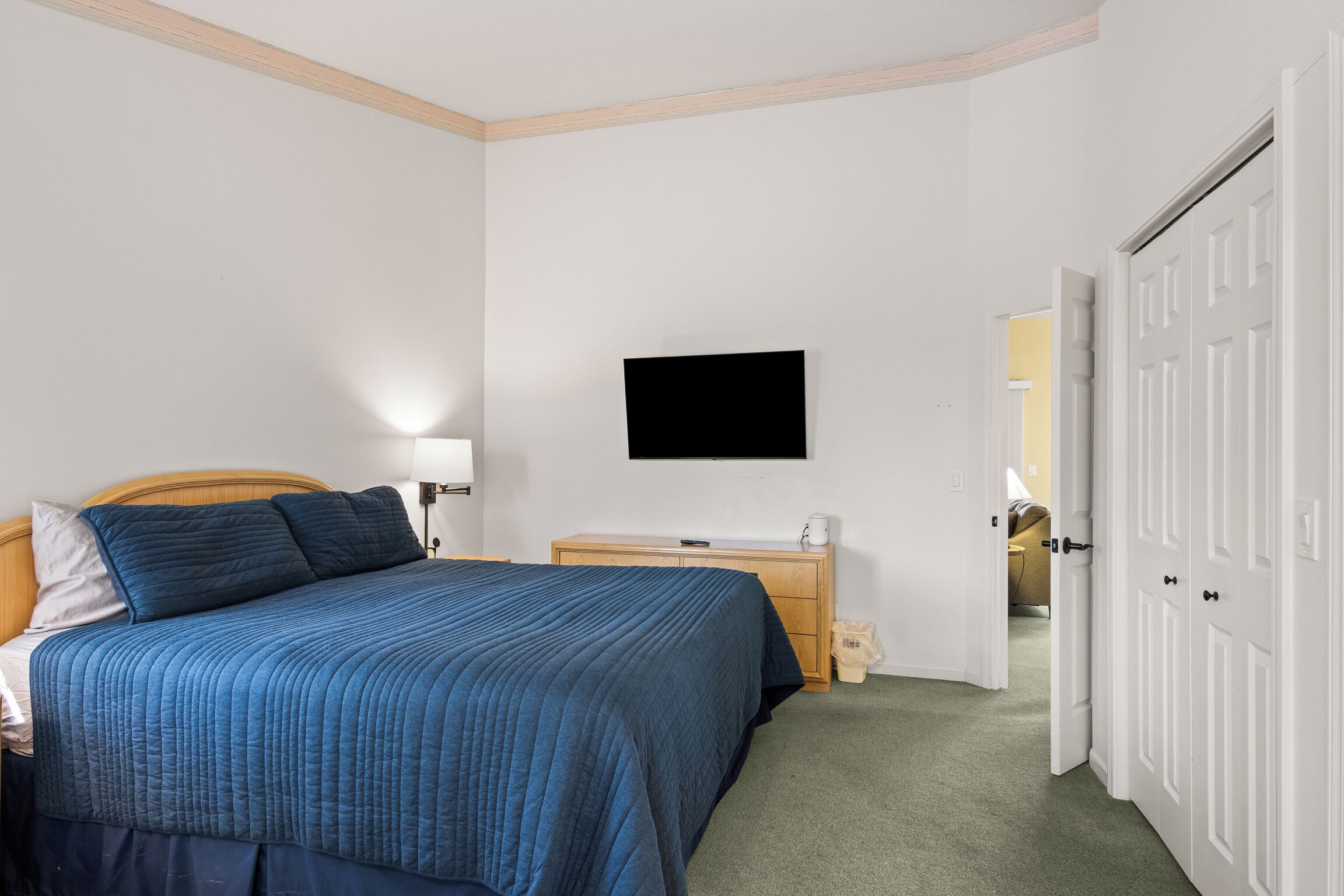 Une chambre à coucher avec un lit, une table de chevet, une lampe et un téléviseur fixé au mur.
