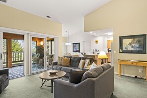 A living room with a sofa, a coffee table, and a dining area with a table and chairs.