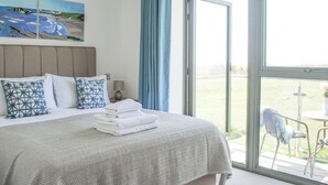 A hotel room with a bed, a painting on the wall, a window with curtains, and a view of the outdoors. - 5 Ocean Reach (Kingsbridge)