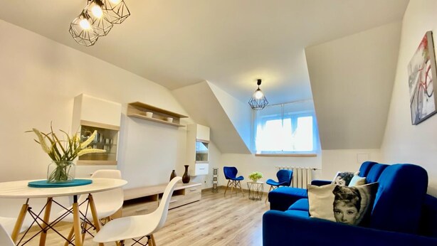 Un loft moderno con comedor, sala de estar con un sofá azul y cocina.