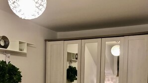 Un dormitorio con un armario grande, una cama, una planta colgante y una araña.