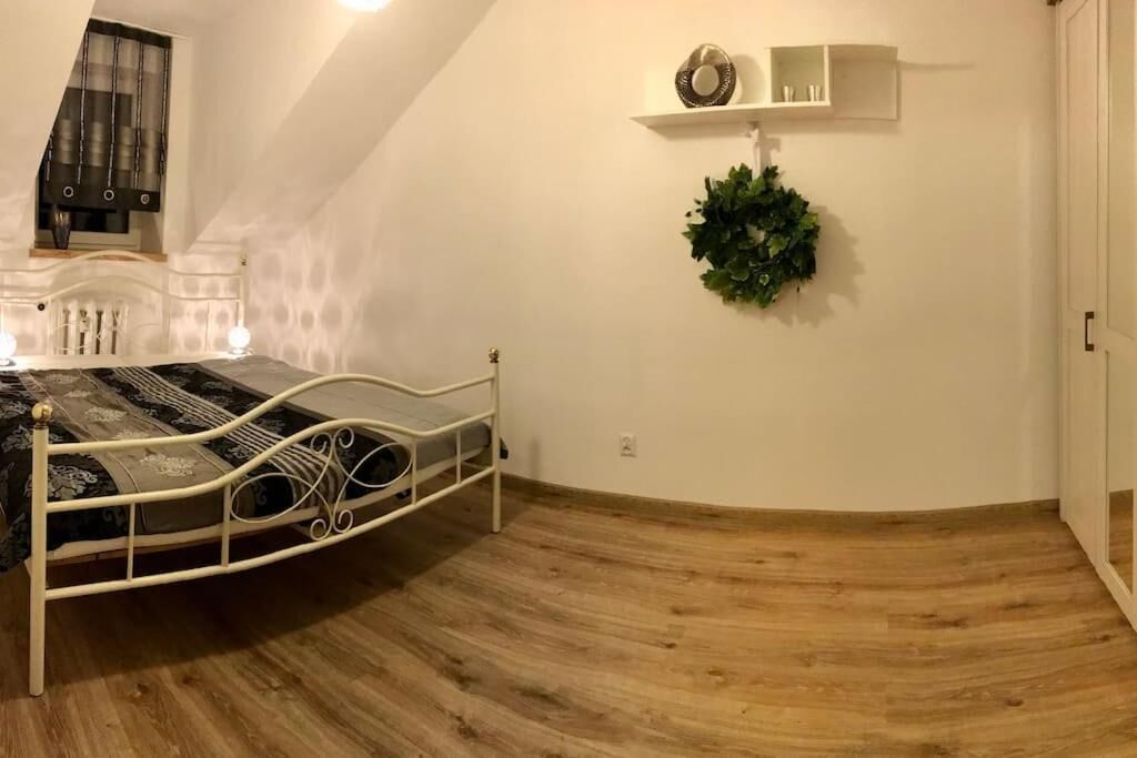 Ein Schlafzimmer mit einem Bett, Holzboden, einer an der Wand befestigten Ablage mit Dekoration und einem Deckenventilator.