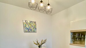 Un comedor moderno con una mesa redonda, sillas blancas y una obra de arte geométrico en la pared.