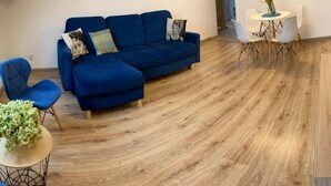 Una sala moderna con un sofá azul, una mesa redonda con sillas y suelo de madera.