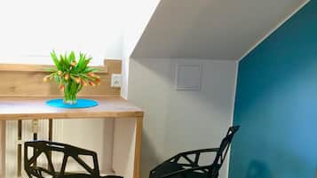 Een kleine kitchenette met een houten aanrecht, twee zwarte stoelen en een potplant.