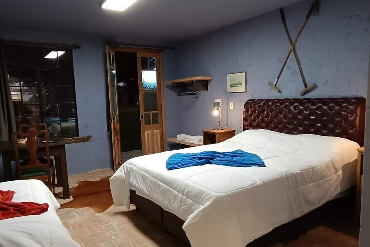 Quarto com uma cama grande, uma mesa pequena, uma cadeira e uma janela.