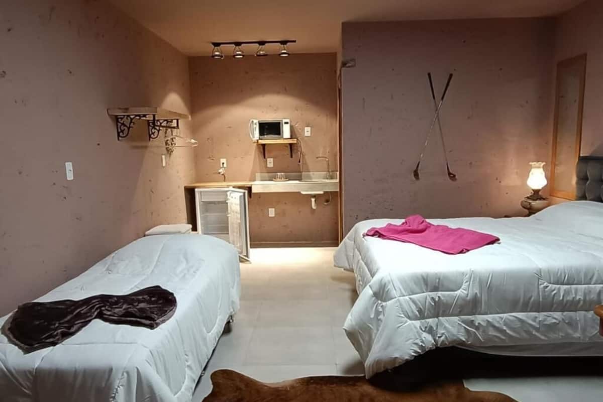 Quarto com duas camas, uma kitchenette e um espelho na parede.
