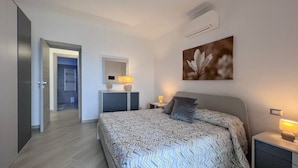 A modern bedroom with a bed, bedside tables, a mirror, and a wall-mounted air conditioner. - Villa Giulia lovely view #2 (Amalfi)
