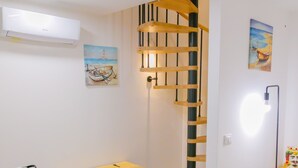 A modern room with a wooden chest, a wooden ladder, a painting, and a ceiling fan.