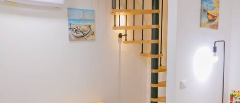 Une chambre moderne avec une commode en bois, une échelle en bois, un tableau et un ventilateur de plafond.