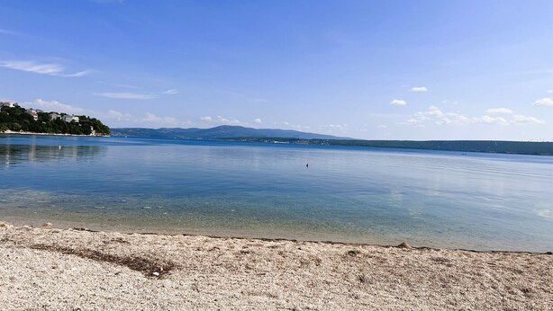 A calm lake with a pebble beach and distant mountains. - Willkommen in der Villa Dobri Dupin, Ihrem Perfekten Urlaubsdomizil am Strand! (Posedarje)