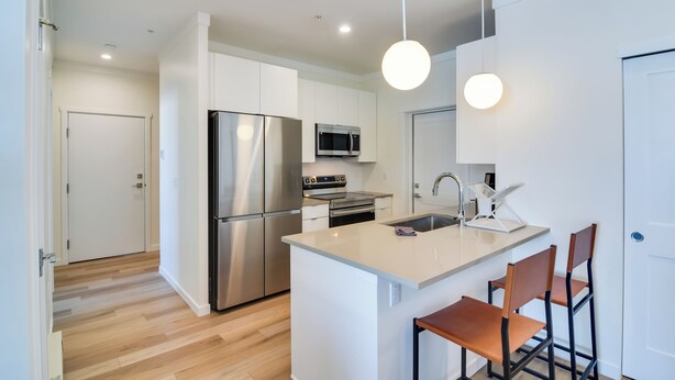 A modern kitchen with stainless steel appliances, a central island with bar stools, and pendant lighting. - 2 Mi to Fraser Tubing Hill: Condo w/ Fireplace! (Fraser)