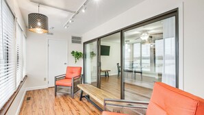 A modern living room with wooden flooring, a glass door leading to a balcony, and orange furniture. - Lakefront Port Clinton Condo w/ Boat Dock & Slip! (Port Clinton)