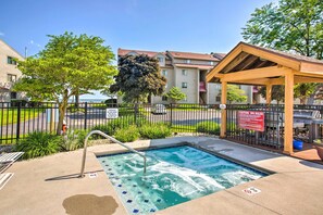 A hot tub area with a wooden pergola, a pool, and a fenced walkway. - Lakefront Port Clinton Condo w/ Boat Dock & Slip! (Port Clinton)