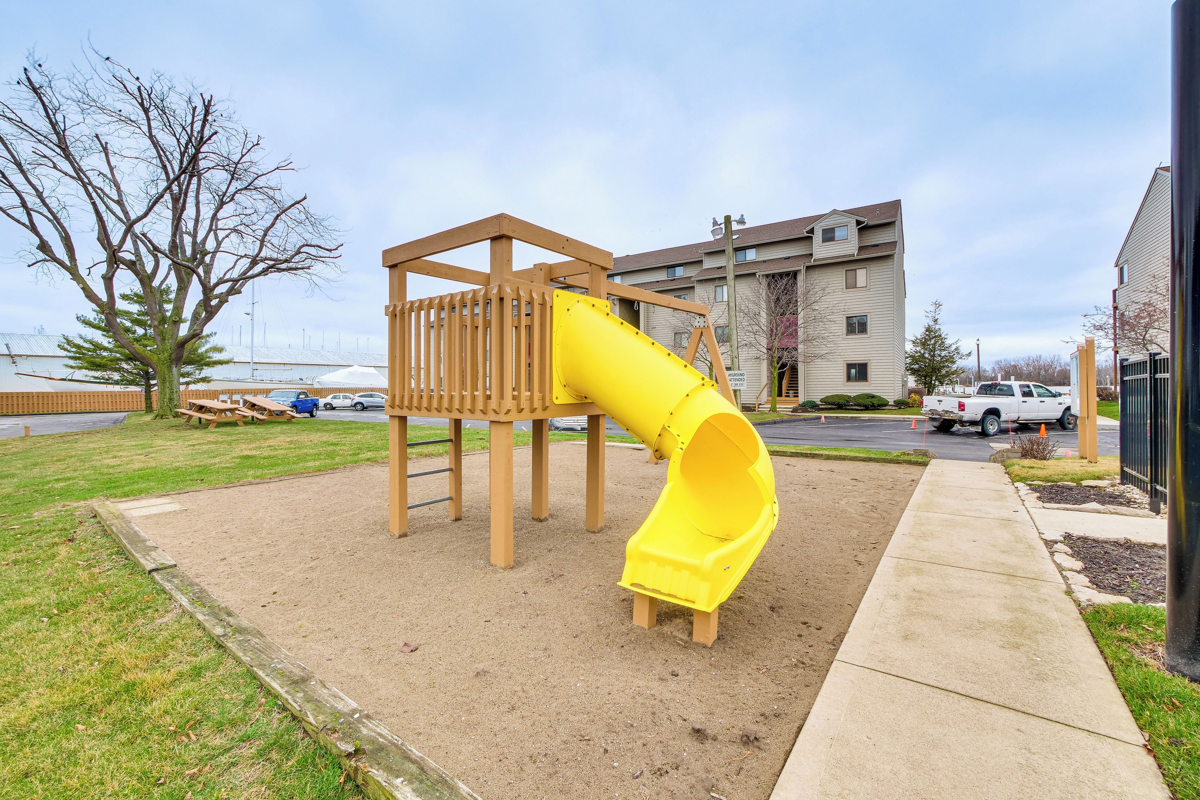 A playground with a yellow slide and a wooden climbing structure.
