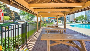 A wooden deck with picnic tables, a pool, and a fenced area with greenery. - Lakefront Port Clinton Condo w/ Boat Dock & Slip! (Port Clinton)