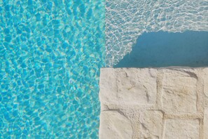 On peut voir clairement une piscine, avec un mur en pierre sur un de ses côtés.